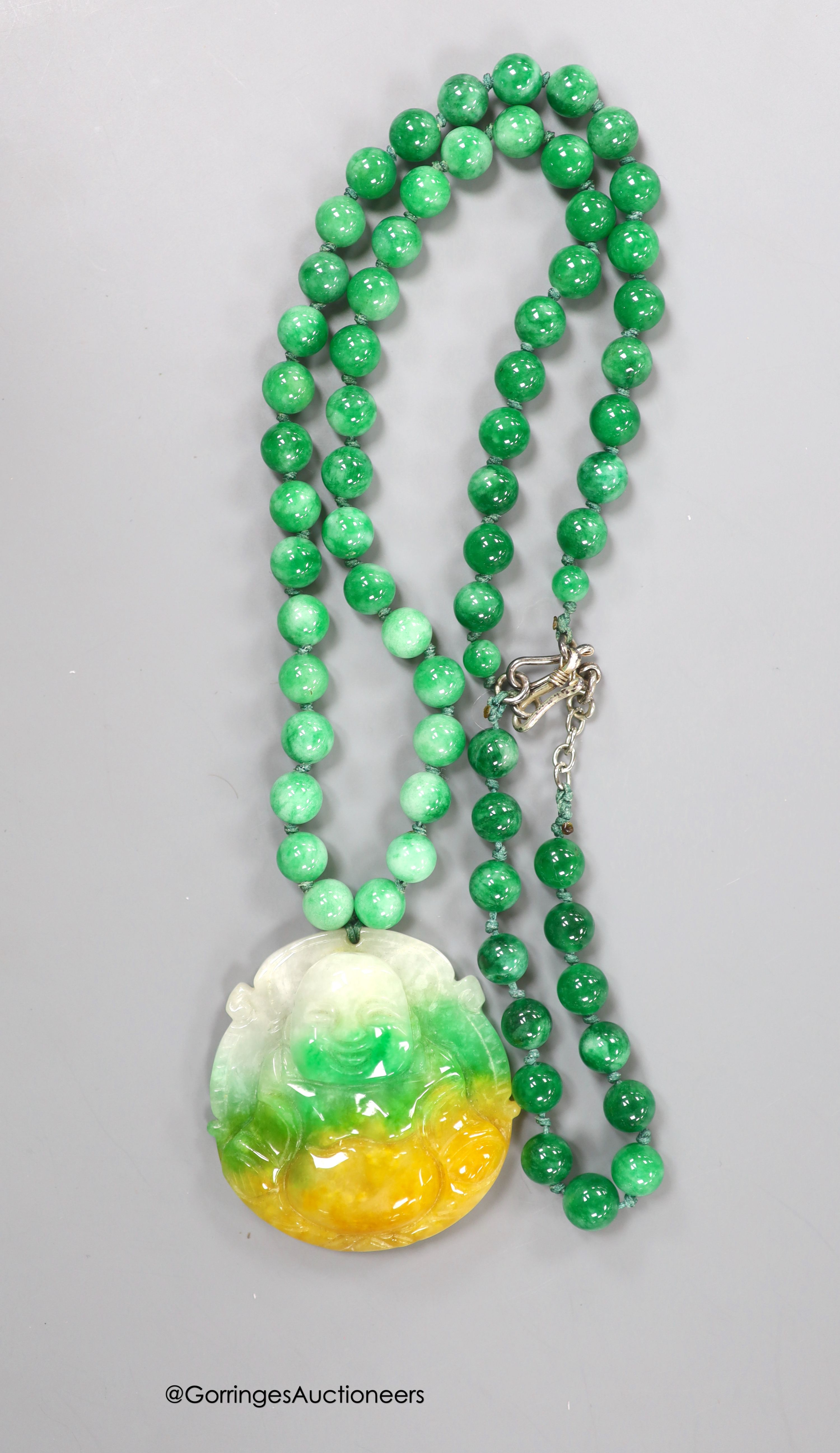 A jade pendant, carved as a Buddha, 50mmm, on a jade bead necklace, 50cm, together with a jade bead bracelet.